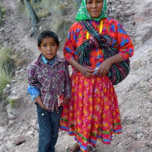 Tarahumara boy with his mother who wears another traditional costume